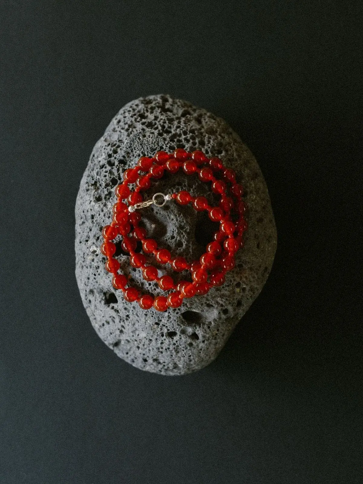 Collar de cuentas rojas sobre una piedra volcánica