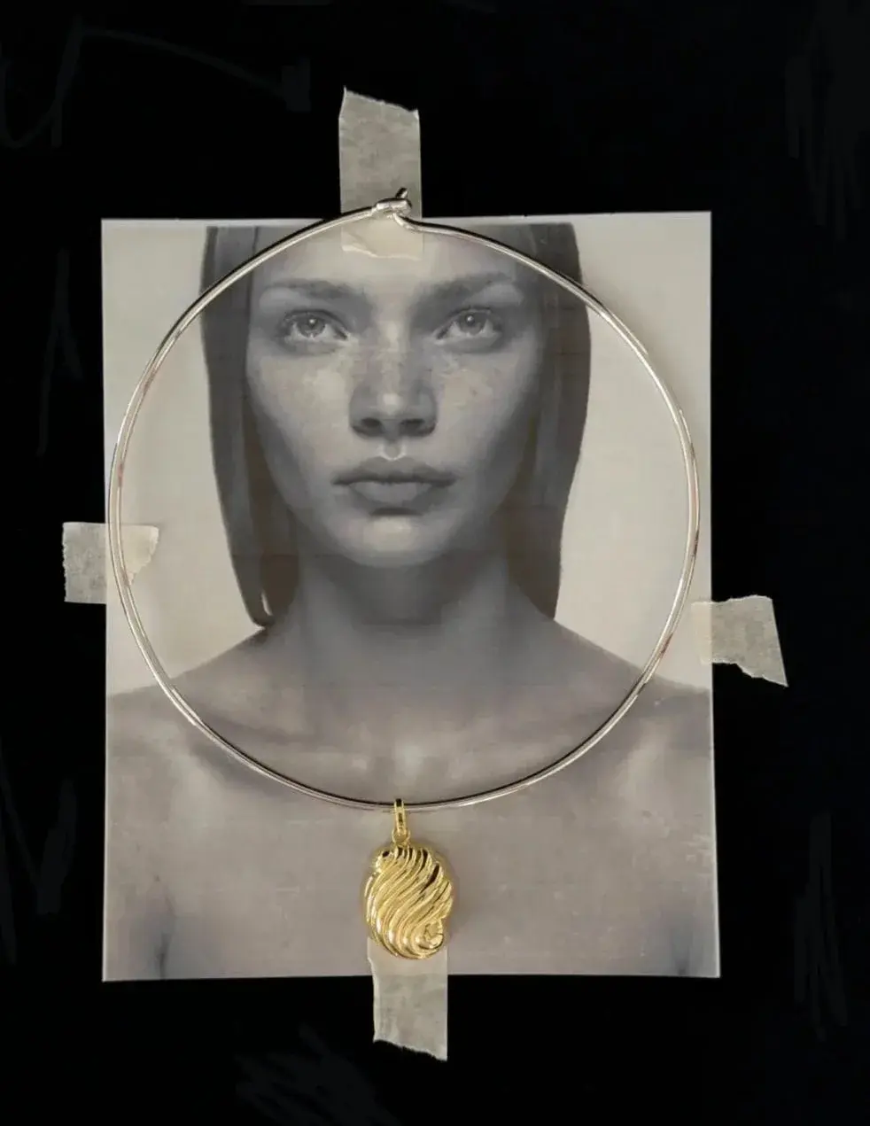 Collar de plata con dije de oro sobre una fotografía en blanco y negro